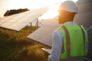 Afrikalı Amerikalı teknisyen güneş panellerinin bakımını kontrol ediyor. Güneş istasyonundaki siyah adam mühendisi.