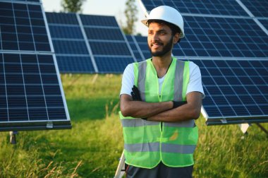 Üniformalı ve aletleri olan Hintli bir işçi güneş paneli çiftliğinde çalışıyor..