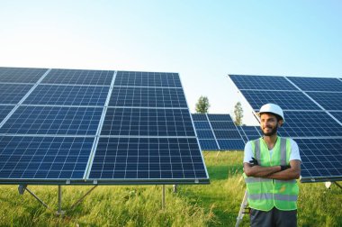 Güneş paneli yakınında çalışan üniformalı Hintli adam.