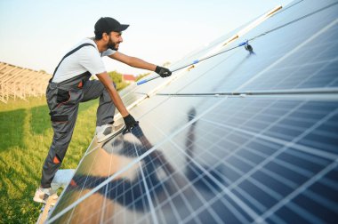 Güneş paneli yakınında çalışan üniformalı Hintli adam.