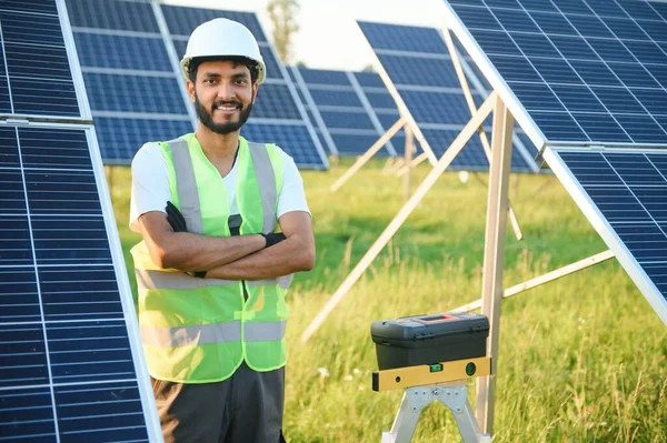 Indian man in uniform working near solar panel