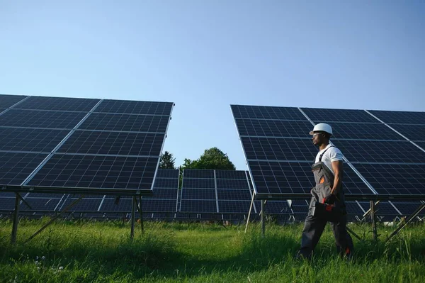 Güvenlik kaskı ve üniforma takan Afro-Amerikan elektrik mühendisinin portresi güneş panelleri kuruyor.
