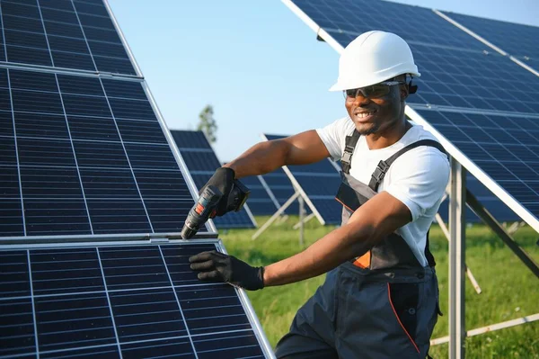 Güvenlik kaskı ve üniforma takan Afro-Amerikan elektrik mühendisinin portresi güneş panelleri kuruyor.