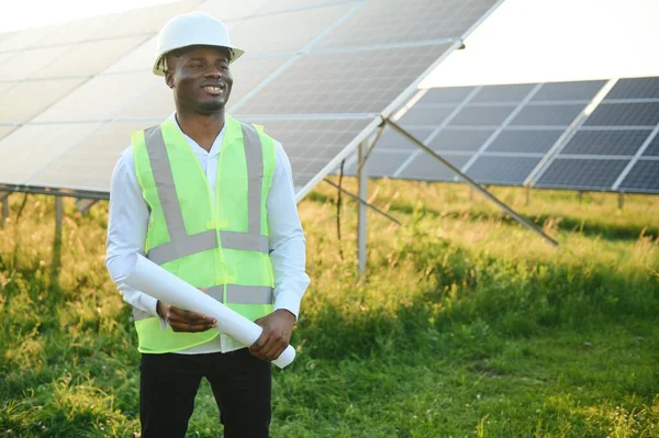 Afrikalı Amerikalı teknisyen güneş panellerinin bakımını kontrol ediyor. Güneş istasyonundaki siyah adam mühendisi.