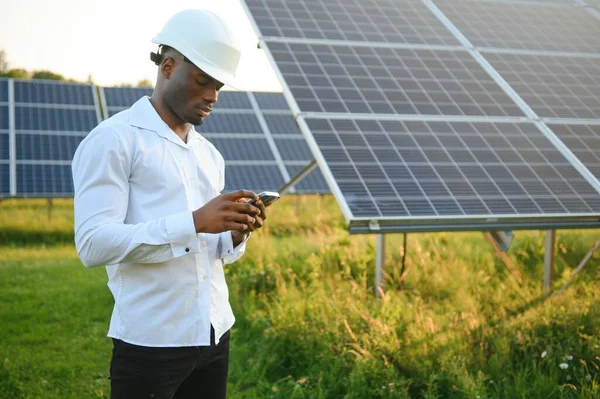 Genç, yakışıklı Afrikalı Amerikalı zanaatkârın yakın portresi koruyucu bir miğfer. Tulumlu, kameraya gülümseyen mutlu bir adam. Yavaş çekim
