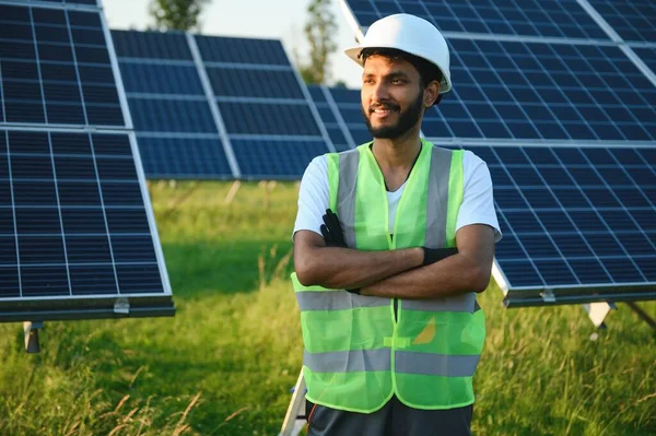 Üniformalı ve aletleri olan Hintli bir işçi güneş paneli çiftliğinde çalışıyor..