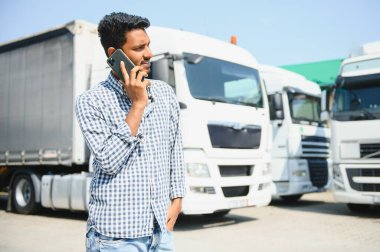 Hintli kamyon şoförü telefonda bir müşteriyle ilgileniyor..