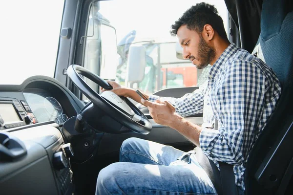 彼のトラックでスマートフォンを使用して若いハンサムなインドの男 ストック画像