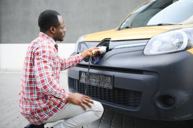 Şık bir adam şarj kablosunu elektrikli arabanın prizine yerleştirir..