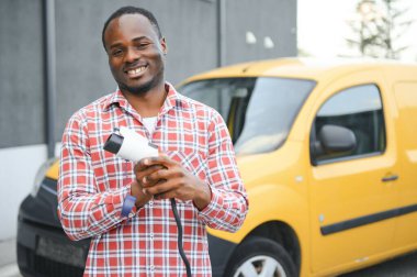 Afrikalı Amerikalı adam elektrikli arabasını şarj ediyor.