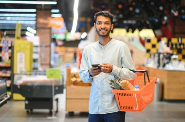 Markette akıllı telefon kullanan Hintli adam.