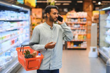 Markette akıllı telefon kullanan Hintli adam.