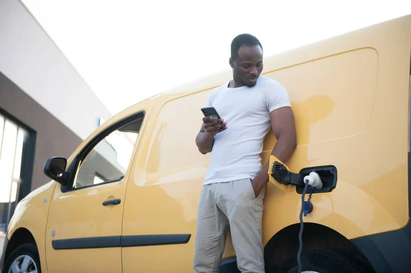 African american man charging car at vehicle charging station.