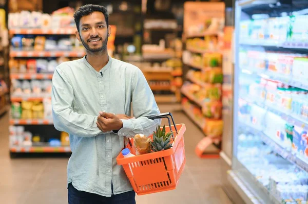 Portrait of happy handsome young Indian at grocery shop or supermarket