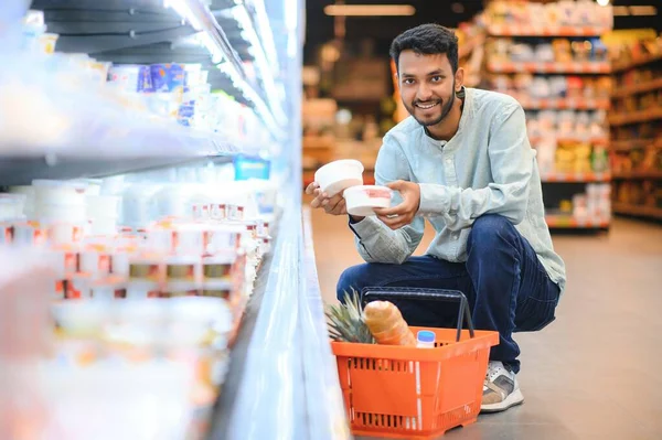 Portrait of happy handsome young Indian at grocery shop or supermarket
