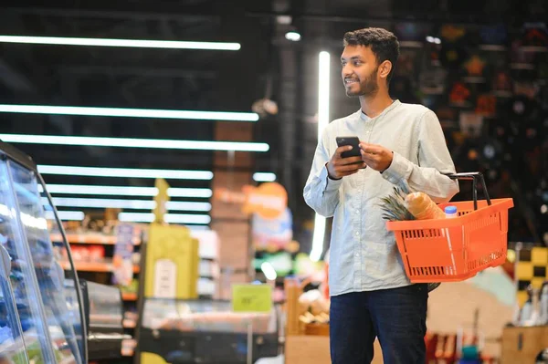 Indian man using smartphone at grocery shop
