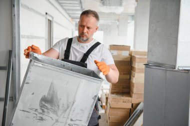Erkek tamirci. Usta havalandırma borularının yanında. Binalar için havalandırma kurulumu. Kameraya geri dönen bir tamirci. Metal havalandırma boruları