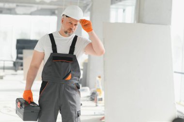 Kasklı ve iş kıyafetli sakallı bir adam. Çalışan bir işçinin fotokopi alanı ile portresi