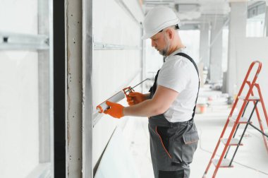 Müteahhit alçı levhalar arasındaki dikişleri silikon tabancayla doldurur..