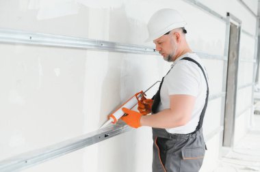 Müteahhit alçı levhalar arasındaki dikişleri silikon tabancayla doldurur..