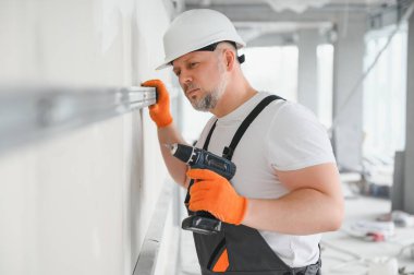 Alçıpan işçisi duvarlara alçı levha yerleştiriyor.