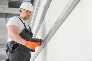 Alçıpan işçisi duvarlara alçı levha yerleştiriyor.