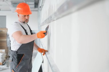 Alçı için mala kullanan alçıpan işçisi sıva beyaz duvara sıva yapıştırıyor.