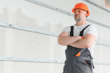 İnsan Mimar. Mimar binanın içinde duruyor. Düşünen inşaatçının portresi. Tamamlanmamış binanın mimarı. İş üniformalı bir mimar.