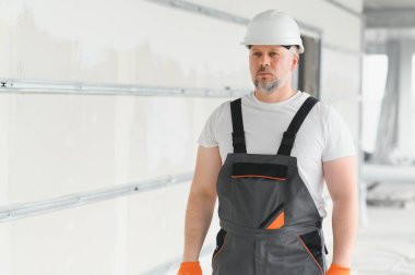 İnsan Mimar. Mimar binanın içinde duruyor. Düşünen inşaatçının portresi. Tamamlanmamış binanın mimarı. İş üniformalı bir mimar.