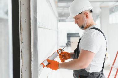 İnşaatçı duvardaki dikişleri mühürlü silikonla dolduruyor..