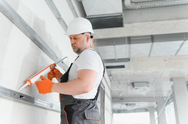 Müteahhit alçı levhalar arasındaki dikişleri silikon tabancayla doldurur..