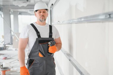 Alçıpan işçisi ya da sıva ve alçı kullanarak duvarlara alçı bant yapıştıran bir adam. Beyaz şapka, iş eldiveni ve güvenlik gözlüğü takıyordu. Kopyalama alanı olan resim