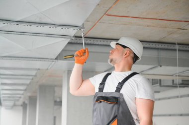Erkek tamirci. Usta havalandırma borularının yanında. Binalar için havalandırma kurulumu. Kameraya geri dönen bir tamirci. Metal havalandırma boruları