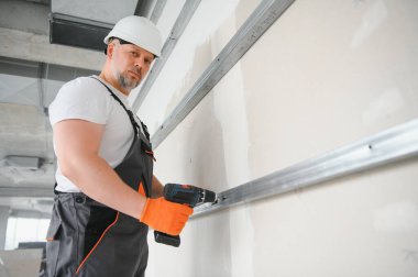 Alçıpan işçisi ya da sıva ve alçı kullanarak duvarlara alçı bant yapıştıran bir adam. Beyaz şapka, iş eldiveni ve güvenlik gözlüğü takıyordu. Kopyalama alanı olan resim