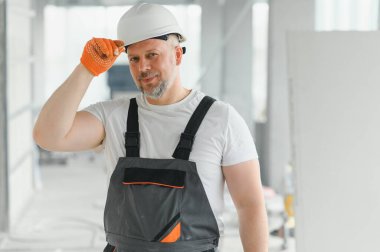 İnsan Mimar. Mimar binanın içinde duruyor. Düşünen inşaatçının portresi. Tamamlanmamış binanın mimarı. İş üniformalı bir mimar.