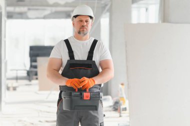 İnsan Mimar. Mimar binanın içinde duruyor. Düşünen inşaatçının portresi. Tamamlanmamış binanın mimarı. İş üniformalı bir mimar.