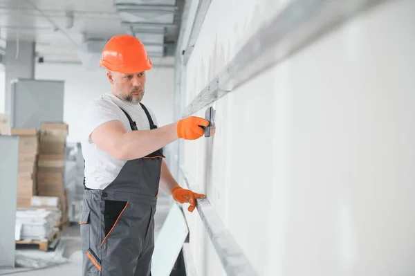 apartment interior construction - worker plastering gypsum board wall.