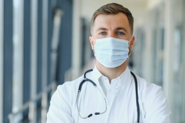 Genç bir erkek doktor genel bir hastanenin koridorunda..
