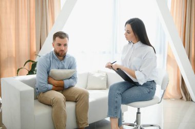 Bir psikologla seans, psikoterapist. Depresyonda olan genç bir erkek hasta ve not defteriyle profesyonel bir kadın doktor. Yaşam tarzı. Ruh sağlığı hizmetleri