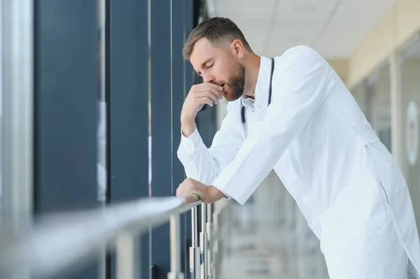 Sad doctor standing in hospital corridor.