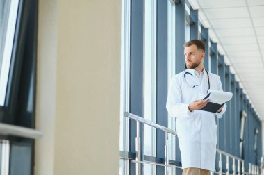 Genç bir erkek doktor genel bir hastanenin koridorunda..