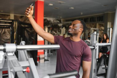 pazı gösterilen ve selfie smartphone ile spor salonunda alarak gülümseyen genç sporcu