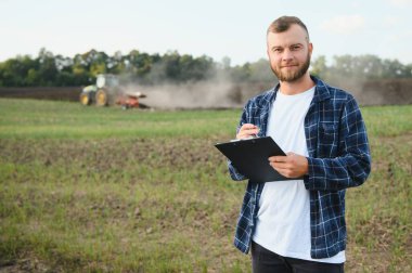 Çerçeve tabletinin üzerindeki alanı kontrol ediyor. Arkaplanda traktör.