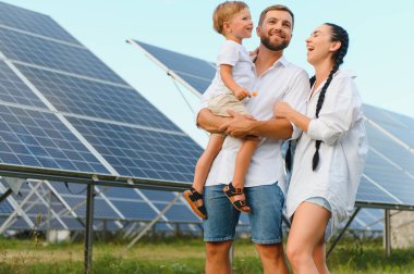 Yeşil enerji kavramı. Mutlu aile yürüyüşleri ve güneş paneli alanında eğlenmeleri. Yeşil enerji