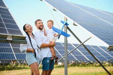 Yeşil enerji kavramı. Mutlu aile yürüyüşleri ve güneş paneli alanında eğlenmeleri. Yeşil enerji