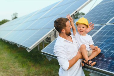 Man showing little child the solar panels during sunny day. Father presenting to his kid modern energy resource. Little steps to alternative energy