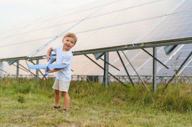 Küçük bir çocuk güneş panellerinin yanında eğleniyor. Güneş enerjisi kavramı