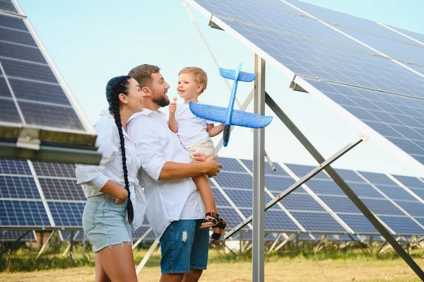 stock image A wide shot of a happy family standing together and smiling at camera with a large solar panel in background.