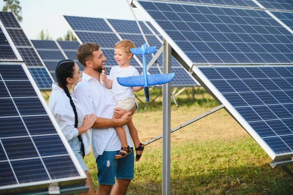 stock image Young family of three is crouching near photovoltaic solar panel, little boy and parents. modern family concept. The concept of green energy.