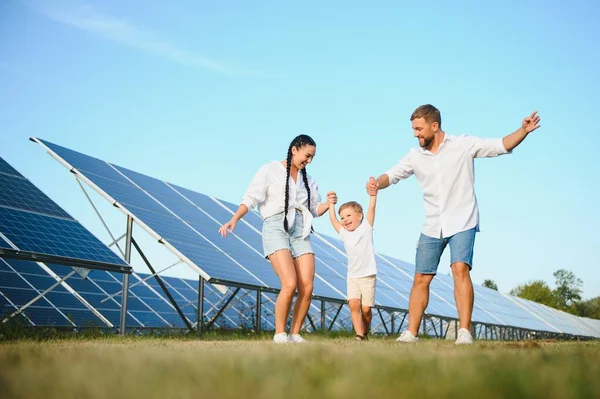 stock image A wide shot of a happy family standing together and smiling at camera with a large solar panel in background.